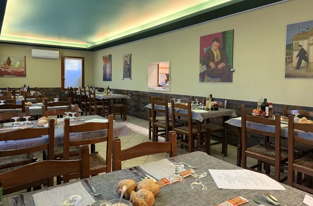 La sala da pranzo con i tavoli apparecchiati e i quadri alle pareti